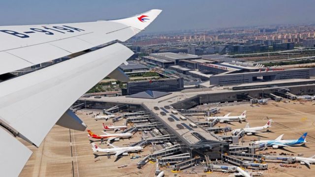 Un avión pasando por encima de un aeropuerto.