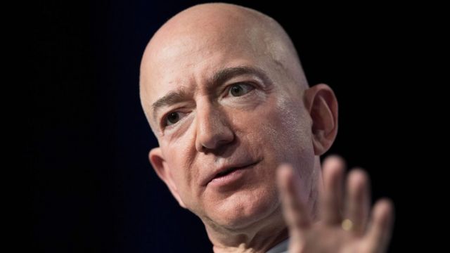 Jeff Bezos gesticulando e falando, na frente de fundo preto