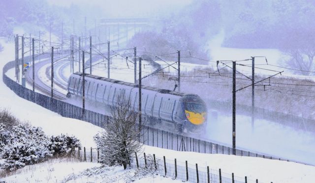 A Eurostar train passes through snow in Ashford, Kent