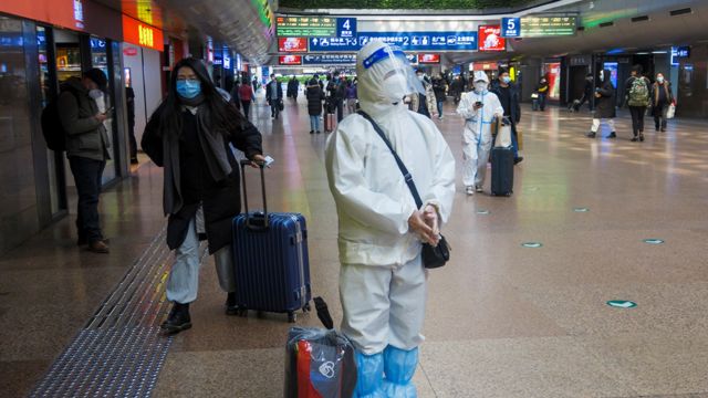 在北京火车站，有旅客身穿防护服，避免感染。