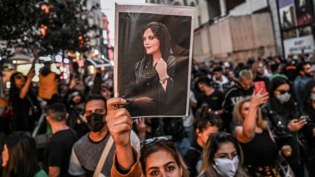 Una mujer muestra la foto de Mahsa Amini en una manifestación
