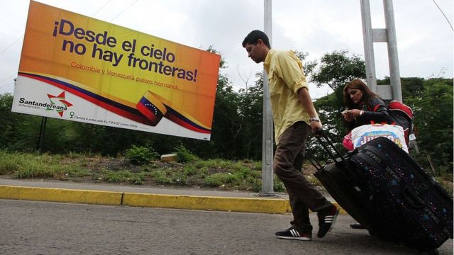 Dos venezolanos cruzan la frontera entre Colombia y Venezuela.