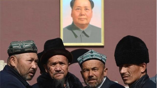 Uighurs pose for photos in front of a portrait of Mao Zedong in Beijing on March 3, 2013