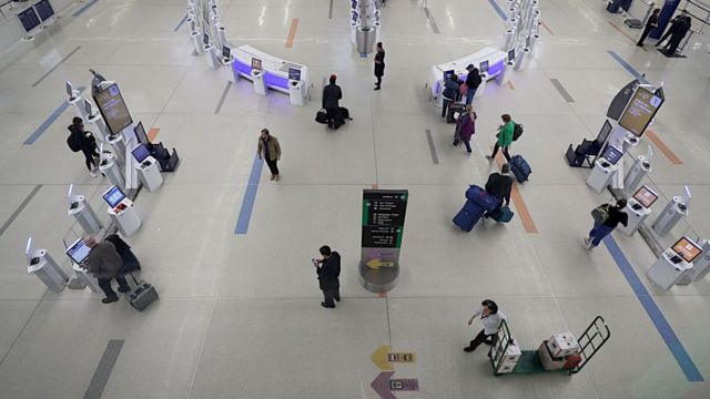 Travelers pass through the check-in lobby of Boston Logan International Airport Terminal B on April 2, 2020