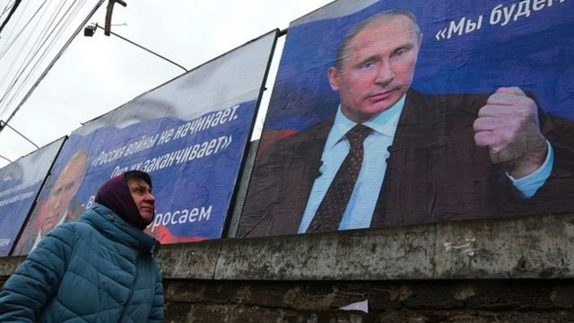 Pessoas passam por um outdoor de Vladimir Putin com a frase: 'A Rússia não começa guerras, acaba com elas', em Simferopol, Crimeia, 10 de março de 2022