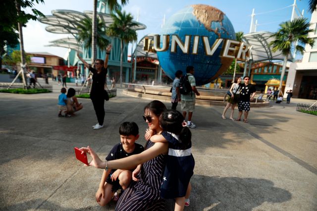 Tourists take selfies outside the Universal Studios theme park in Sentosa in Singapore,