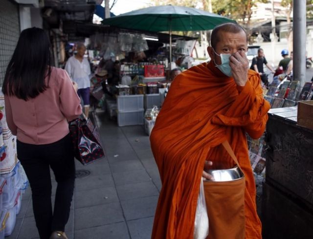 A Buddhist monk adjusts his face mask while on his way for morning alms in Bangkok, Thailand, 04 March 2020