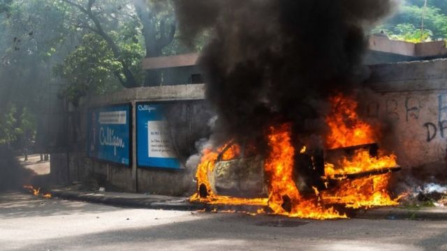 Un'auto in fiamme in una strada di Port-au-Prince