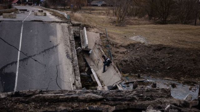 Un hombre intenta cruzar un puente colapsado en Irpín