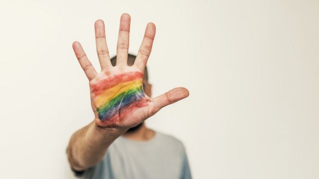 Человек с радужным флагом, нарисованным на ладони