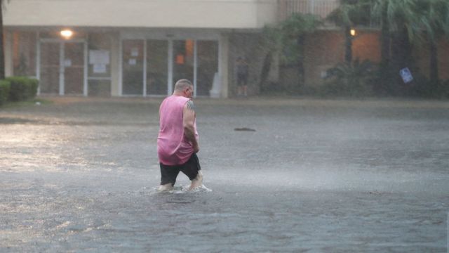 A man wades through a flooded car park in Gulf Shores, Alabama