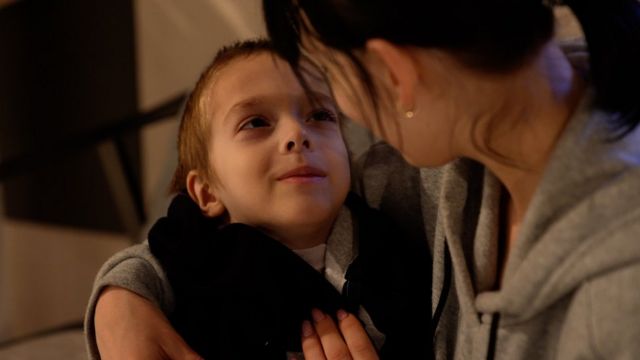 A boy with cancer looks at his mother.