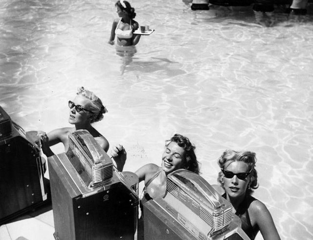 Tres mujeres jugando en máquinas tragamonedas en la piscina