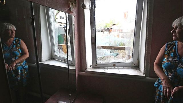 Жінка дивиться в розбите вікно