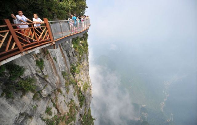 Gente camina sobre un puente de cristal en el Parque forestal nacional Zhangjiajie.