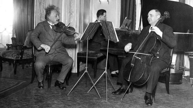 Einstein sentado tocando violino junto com outros músicos