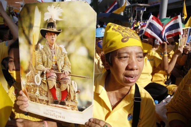 People holding a figure of Rama 10