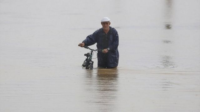 Hombre en biccleta en medio de una inundacion