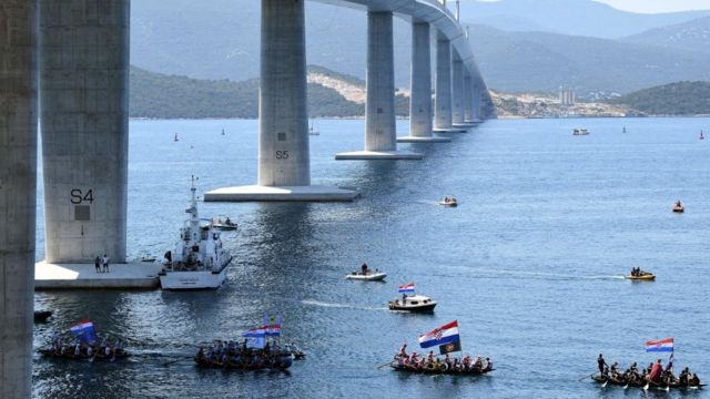 Croatian boats sail under the bridge to celebrate the opening