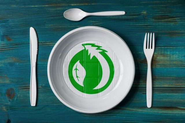 A plastic plate and cutlery with environmental green logo (stock photo)