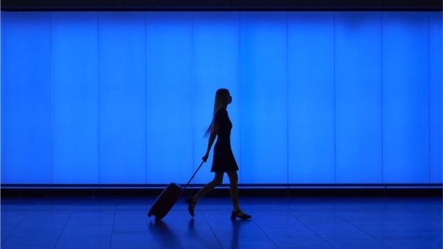 Mulher carrega mala em aeroporto