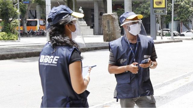 Dois agentes do censo usando máscaras e viseira no rosto
