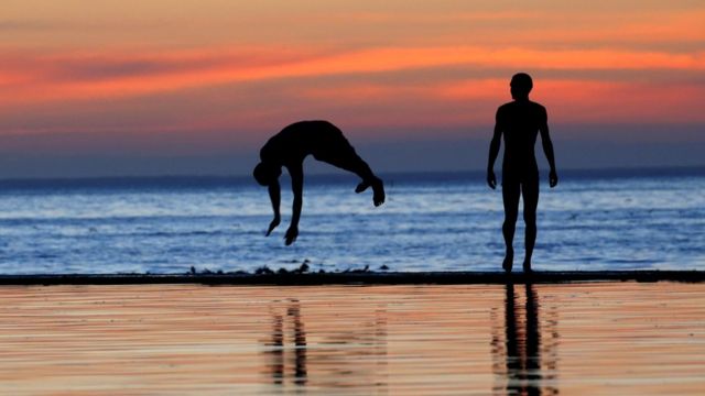 Wani saurayi ya yi daka-tsari a cikin ruwa ranar Asabar a fitaccen bakin tekun nan na Camps Bay da ke birnin Cape Town, na Afirka ta kudu yayin da ake fama da zafi.