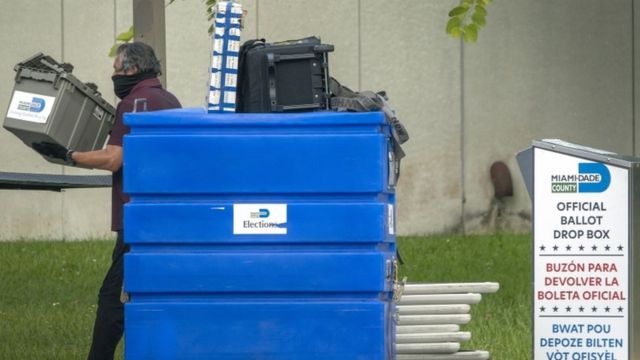 Homem carregando urnas após primárias nos Estados Unidos