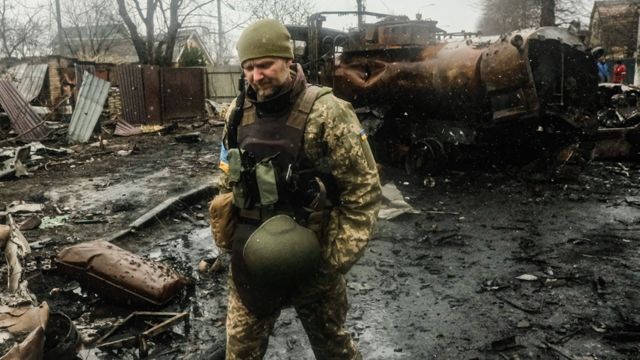 A Ukrainian soldier inspects the wreckage of a destroyed Russian armoured column on a road in Bucha, a suburb north of Kyiv on 3 April 2022