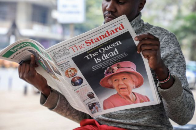 یک فروشنده روزنامه در حال خواندن یک روزنامه محلی در مورد مرگ ملکه الیزابت دوم در شهر نایروبی