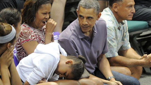 大学バスケットボールの試合で眠そうな小さなサーシャ・オバマさん。お母さんのミシェル夫人も同感のようだ