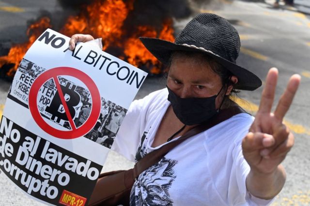 Mulher com cartaz contra bitcoin.