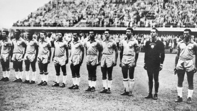 Foto em preto e branco mostra jogadores lado a lado no campo, aparentemente posando para foto