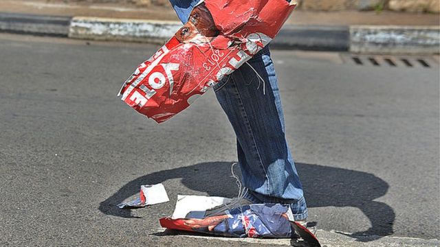 Ushyigikiye ihuriro CORD riyobowe na Raila Odinga ahonyoye icyapa cya Perezida watowe wa Kenya Uhuru Kenyatta, ku itariki ya 16 y'ukwezi kwa gatatu mu 2013, hanze y'inyubako y'urukiko rw'ikirenga, aho urubyiruko rwari rwateraniye mu gushyigikira ubusabe bwo kwamagana amatora rusange ya Kenya