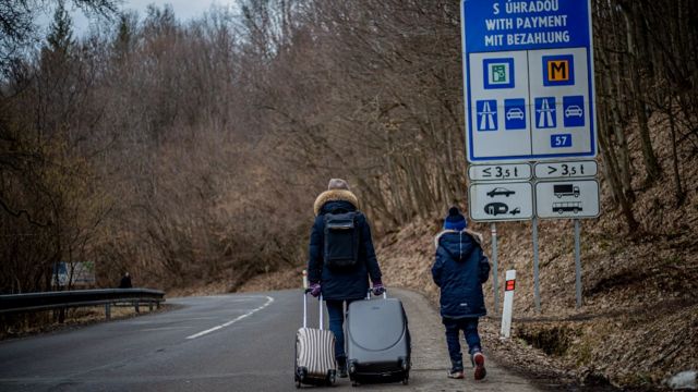 Una madre y su hijo caminan por la carretera con sus maletas y bolsos