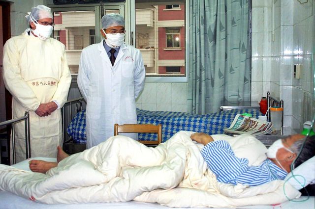 Robert Maguire de la OMS y un médico chino visitan a un paciente con SARS en Guangzhou, China - abril de 2003