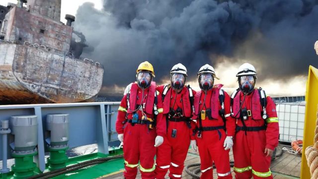 It shows four Chinese rescuers posing for a picture before boarding the burning oil tanker "Shanchi" at sea off the coast of eastern China, a day before the Iranian oil tanker burst into flames from end to end and sank.