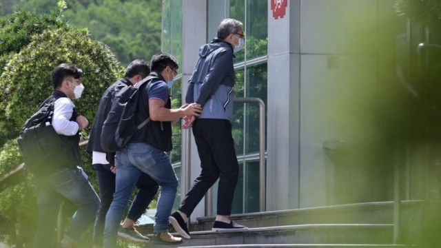 香港警方国安处便装警员把壹传媒行政总裁张剑虹（中）押入壹传媒总部大楼（17/6/2021）