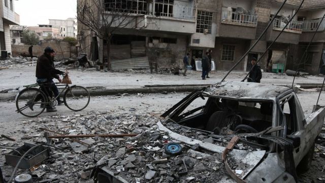 رجال وسط آثار القصف الجوي في الغوطة الشرقية