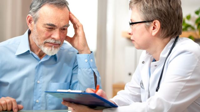Uma médica examina um homem mais velho