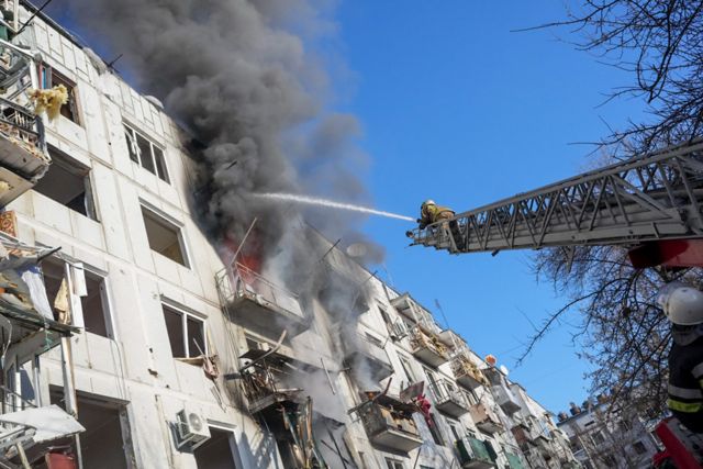 乌克兰楚胡伊夫市区一栋公寓楼遭炮轰起火，消防队员设法灭火。(photo:BBC)