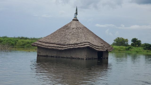 Casa de barro com telhado de palha é inundada por água de rio