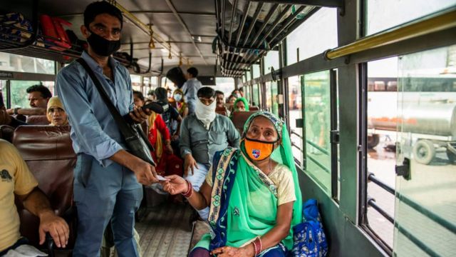 A bus conductor issues tickets to a female passenger in Uttar Pradesh.