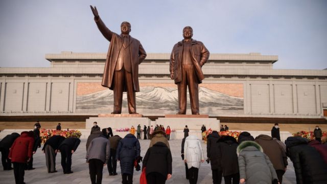 People bow in front of statues of the late North Korean leaders Kim Il Sung and Kim Jong Il in February 2021.