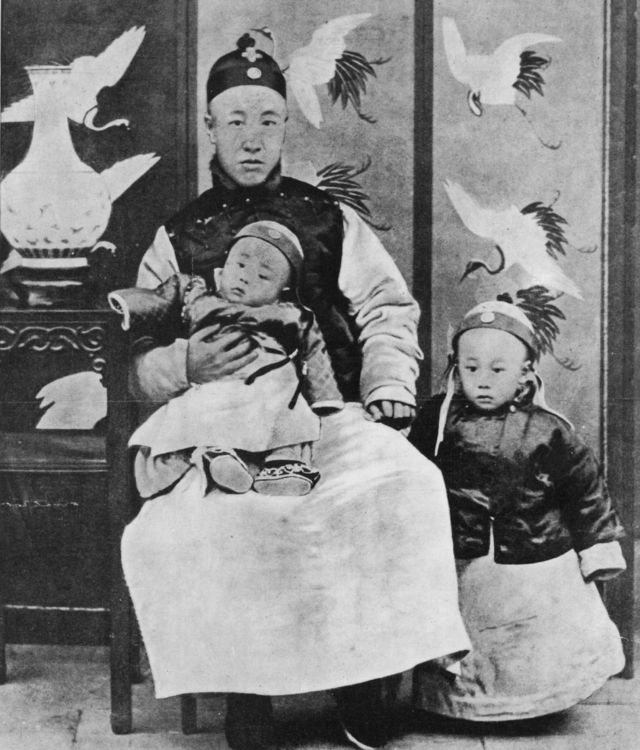 1909: Príncipe Chun, regente y controlador de la Nación, con su hijo menor de rodillas y Puyi (1906-1967) Emperador de China, a su lado.