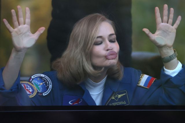 Actress Yulia Peresild blows a kiss through a bus window as she leaves for the Baikonur Cosmodrome, Kazakhstan, on 5 October 2021