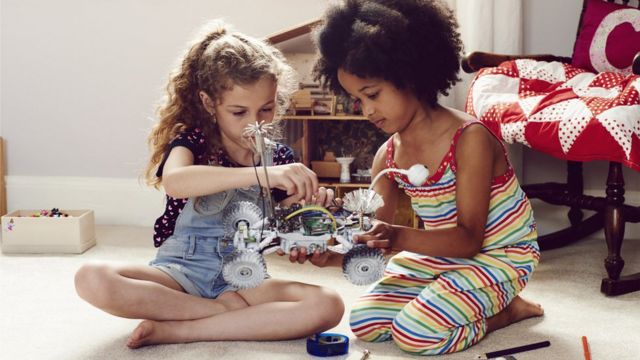 Dos niñas juegan con un vehículo.