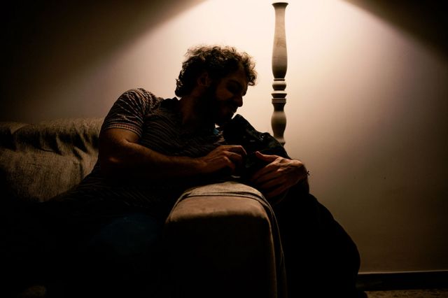 A man sits on his sofa with his guide dog