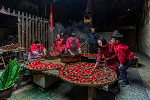 "Fujian'daki Şianlian Köyü'nde küçük bir çiftlik evinde çekilen bu fotoğrafta bir aile, Çin usulü pirinç veya fasulyeyle doldurulan mantılarını hazırlamak için bir araya gelmiş. Kırmızı hamura tahta çubuklarla talih veya mutluluk yazıyor, sonra da buharda pişiriyorlar."