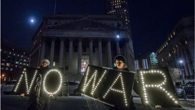 Manifestantes con luces que dicen No War